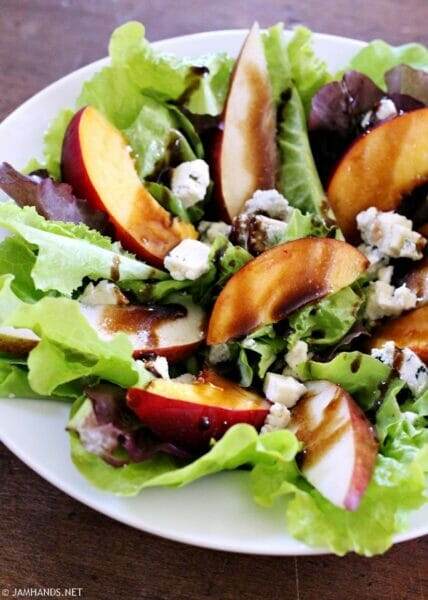 Large white salad bowl filled with Pear & Nectarine Salad with Gorgonzola and Pear Balsamic Dressing.