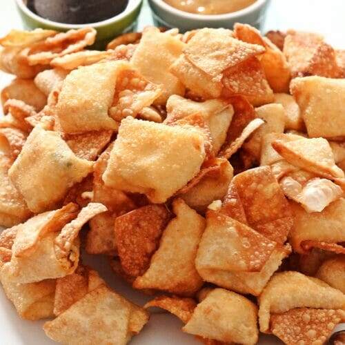 Large platter of fried Crab Rangoon, with a side of soy sauce and hot mustard in ramekins.