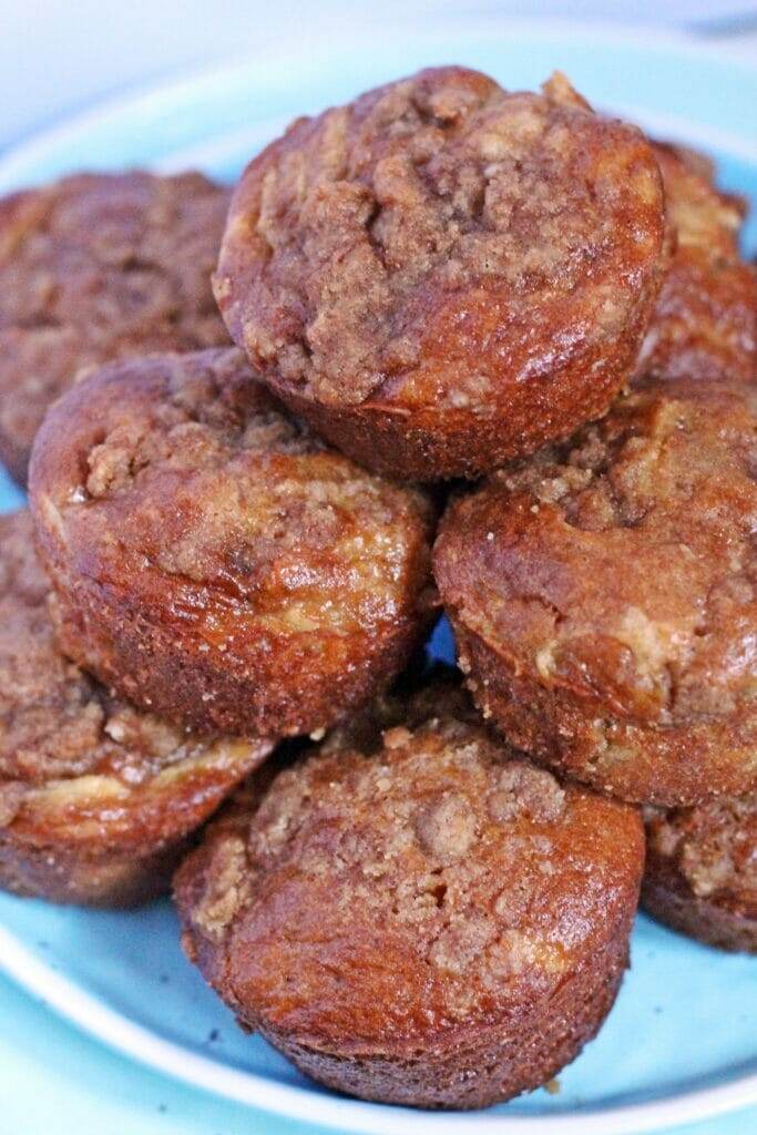 Apple Pie Streusel Muffins stacked on a blue plate.