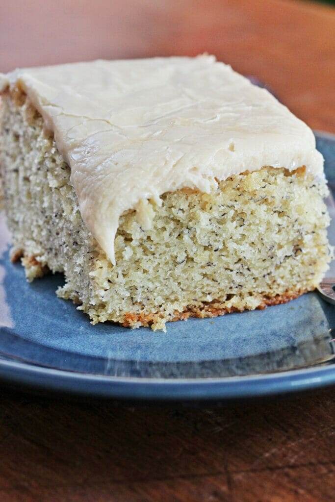 A slice of Banana Cake with Caramel Frosting on a blue plate, garnished with caramel frosting. Moist and delicious!