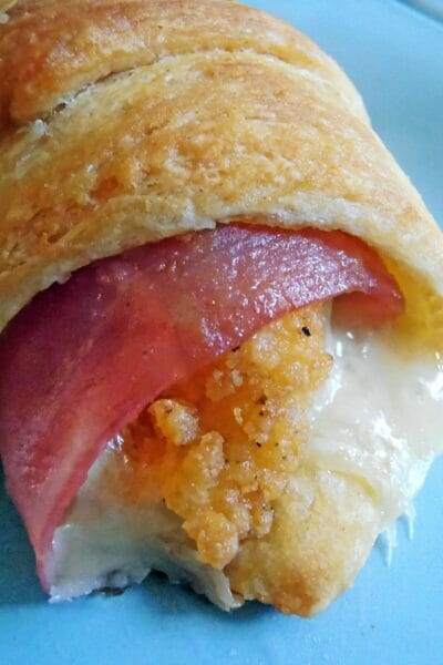 A plate of golden-brown Chicken Cordon Bleu Crescents, made with crescent roll dough, filled with chicken fingers, ham, and swiss cheese, baked to perfection. A delicious and easy meal or appetizer option.