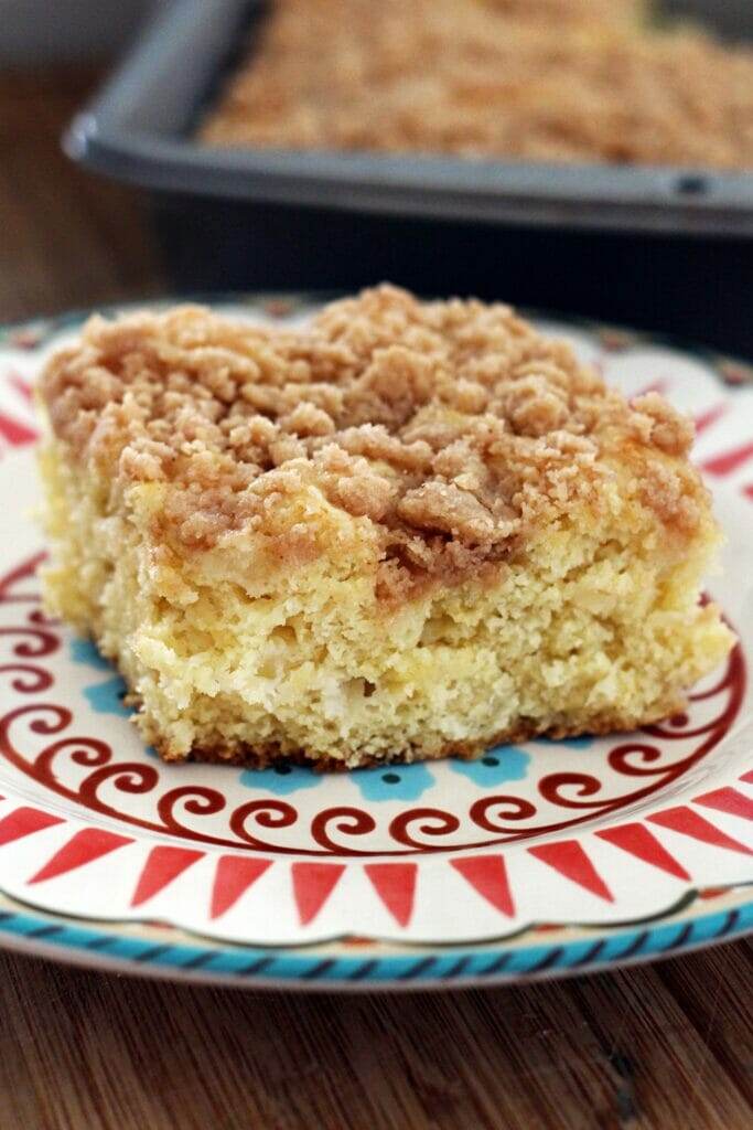 A slice of moist Pineapple Coffeecake with a golden streusel topping, served on a plate with a fork. Perfect for brunch or breakfast. #PineappleCoffeecake #StreuselTopping #BrunchRecipes