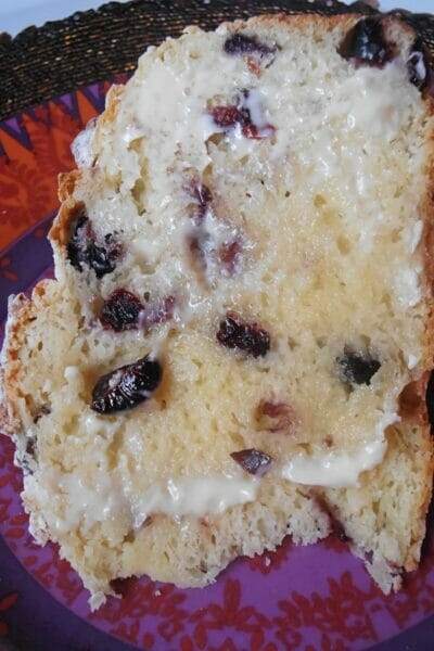 Image of a warmed and buttered slice of Sweet Cranberry Irish Soda Bread on a colorful plate.