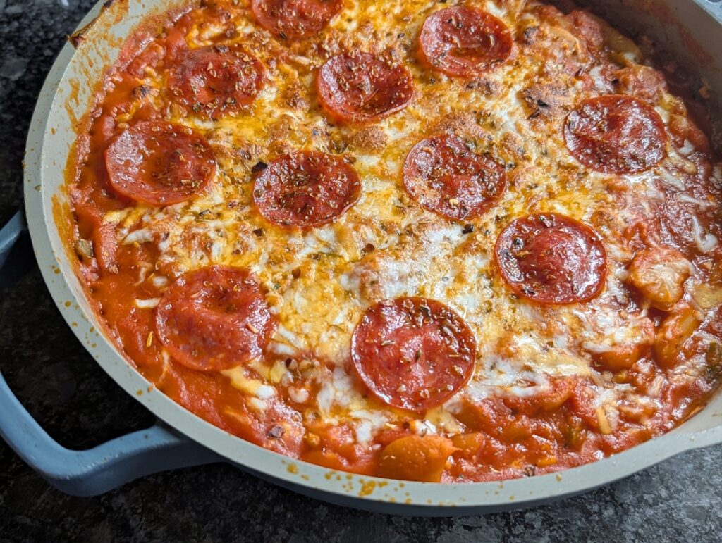 Close up photo of baked pizza beans with melted and browned cheese on top with crispy pepperoni.